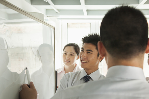 A group of coworkers look at a white board together